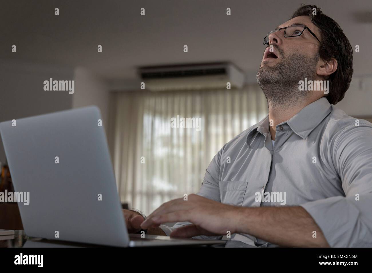 Brazilian man tired while working from home, doing home office, during the day Stock Photo