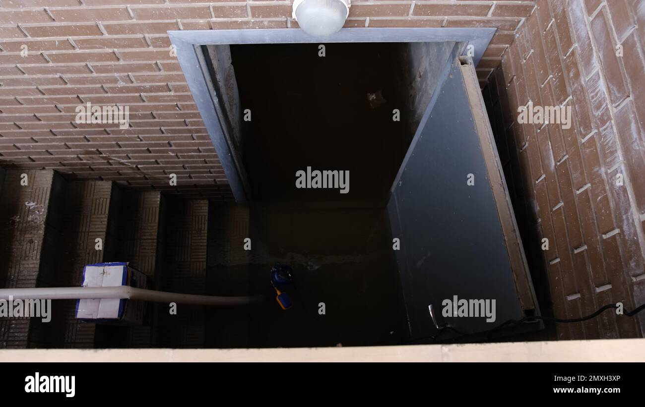 Recently flooded basement seen with a large pipe and pump used to pump out flooded basement