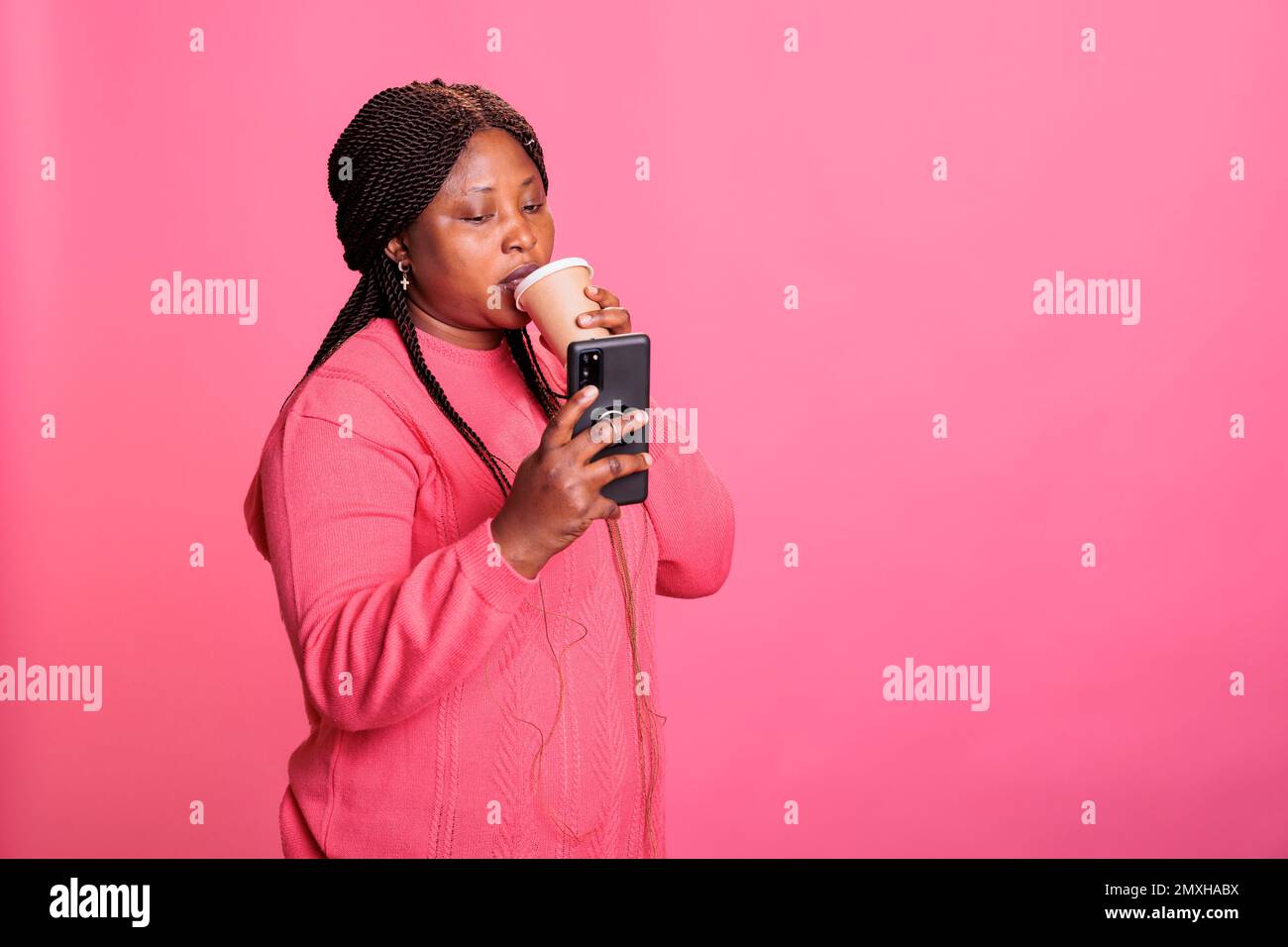 Positive cheerful model drinking coffee while enjoying lesiure time in