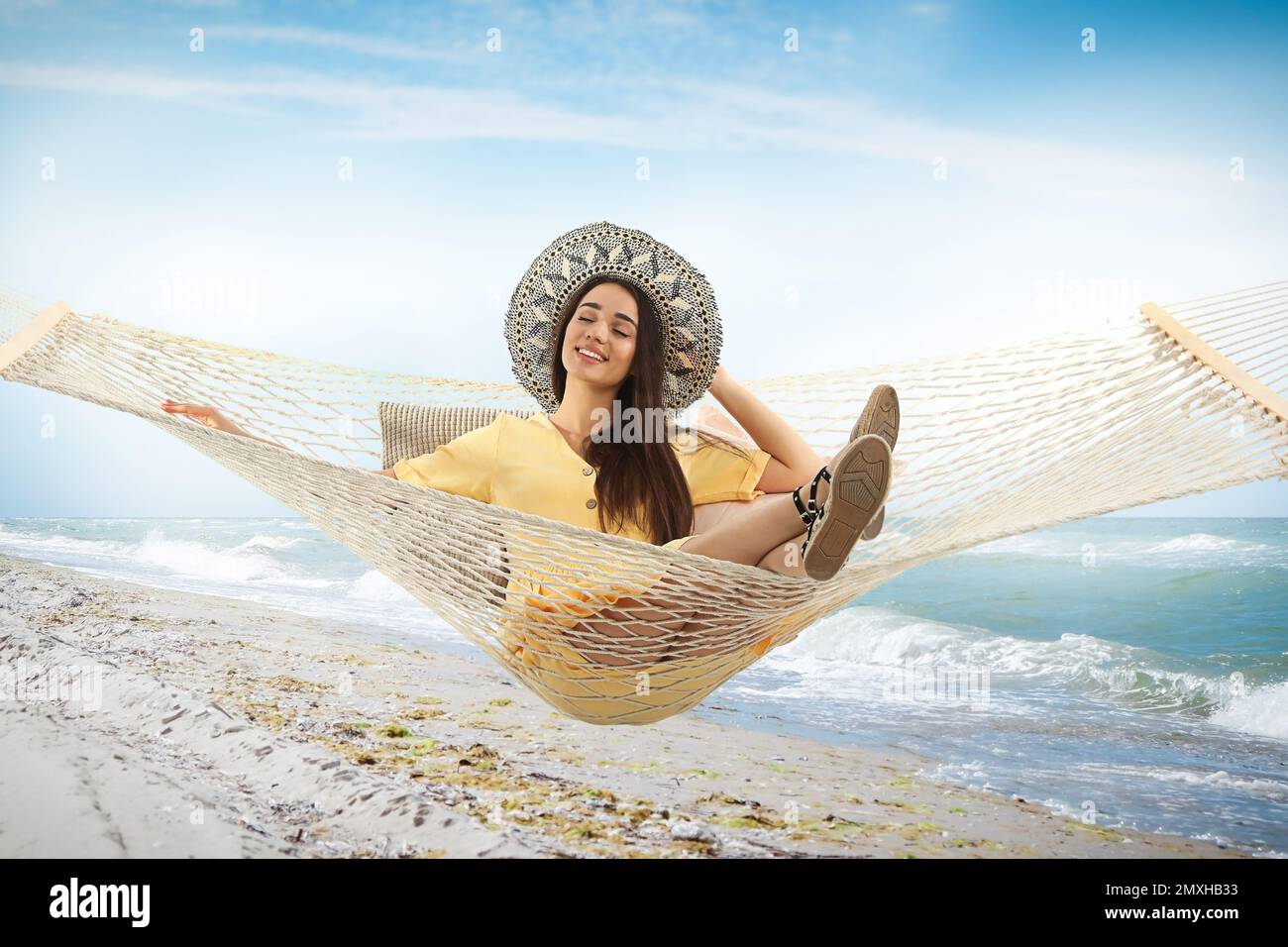 Woman resting in hammock near sea on sunny day Stock Photo