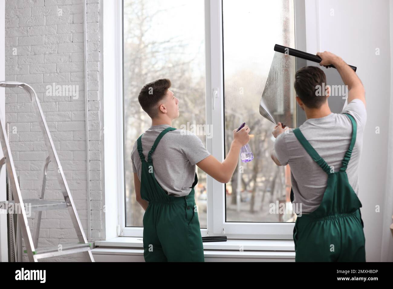 Professional workers tinting window with foil indoors Stock Photo