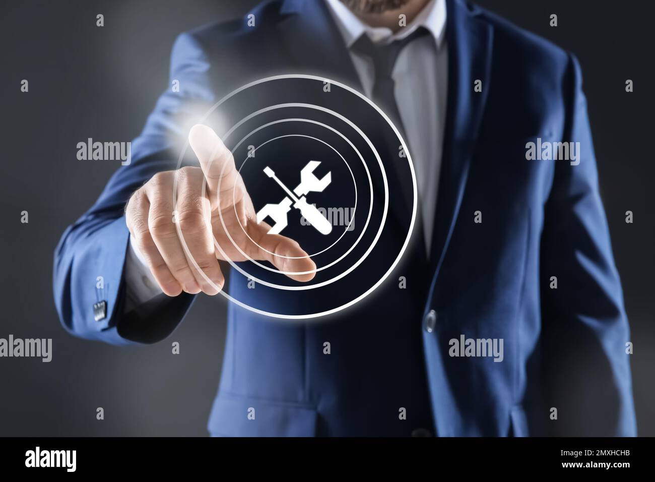 Man touching icon on virtual screen against dark background, closeup. Technical support Stock Photo