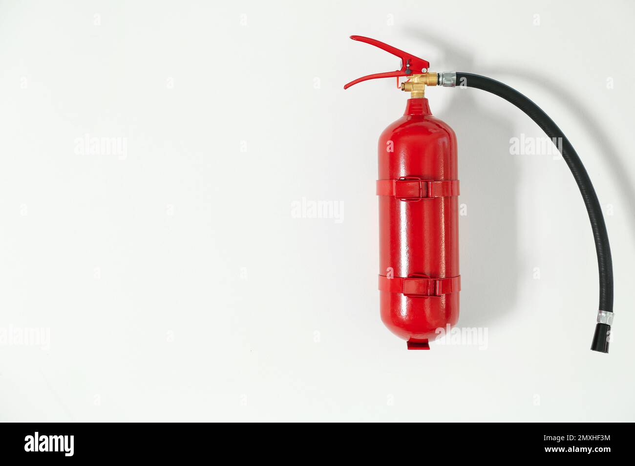 Fire extinguisher hanging on white wall, space for text Stock Photo Alamy