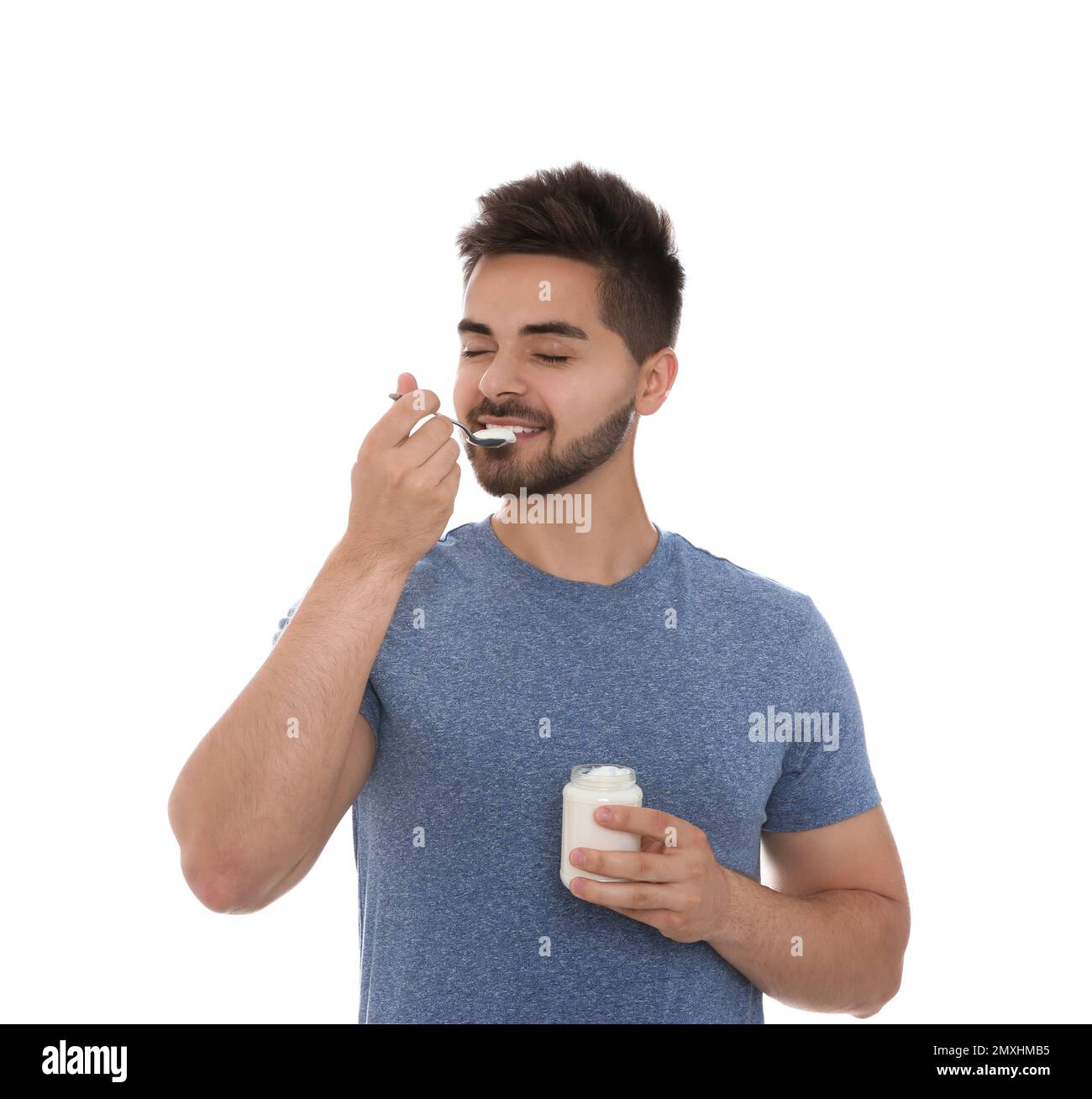 Happy young man eating tasty yogurt on white background Stock Photo Alamy