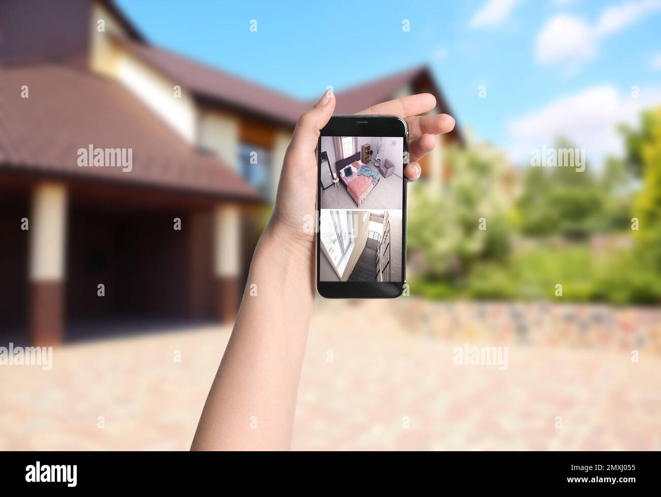 Woman monitoring modern CCTV cameras on smartphone near her house ...