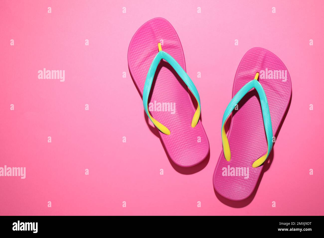 Pair of stylish flip flops on pink background, top view with space for ...