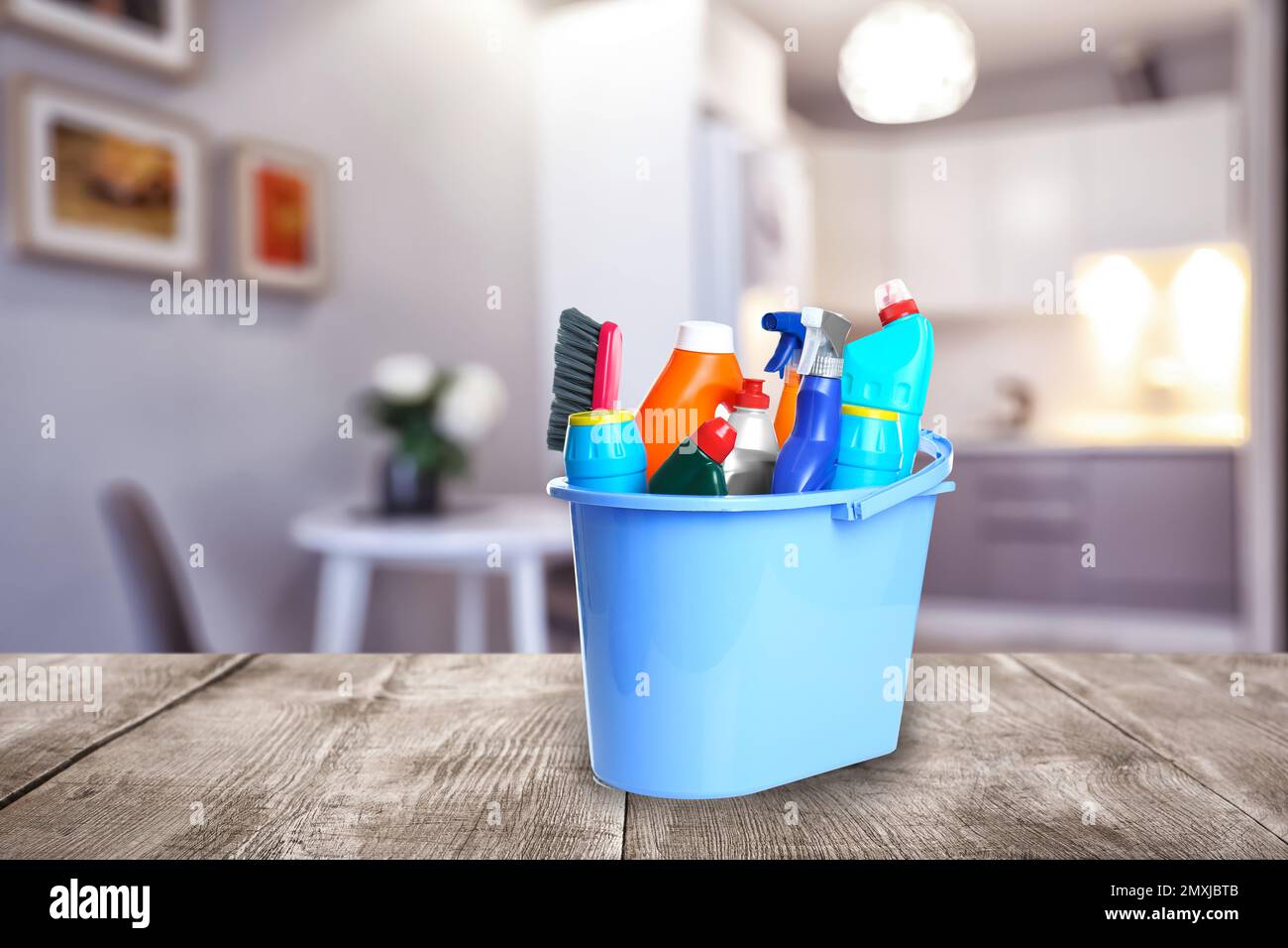 Bucket with cleaning supplies on wooden surface in modern room Stock ...
