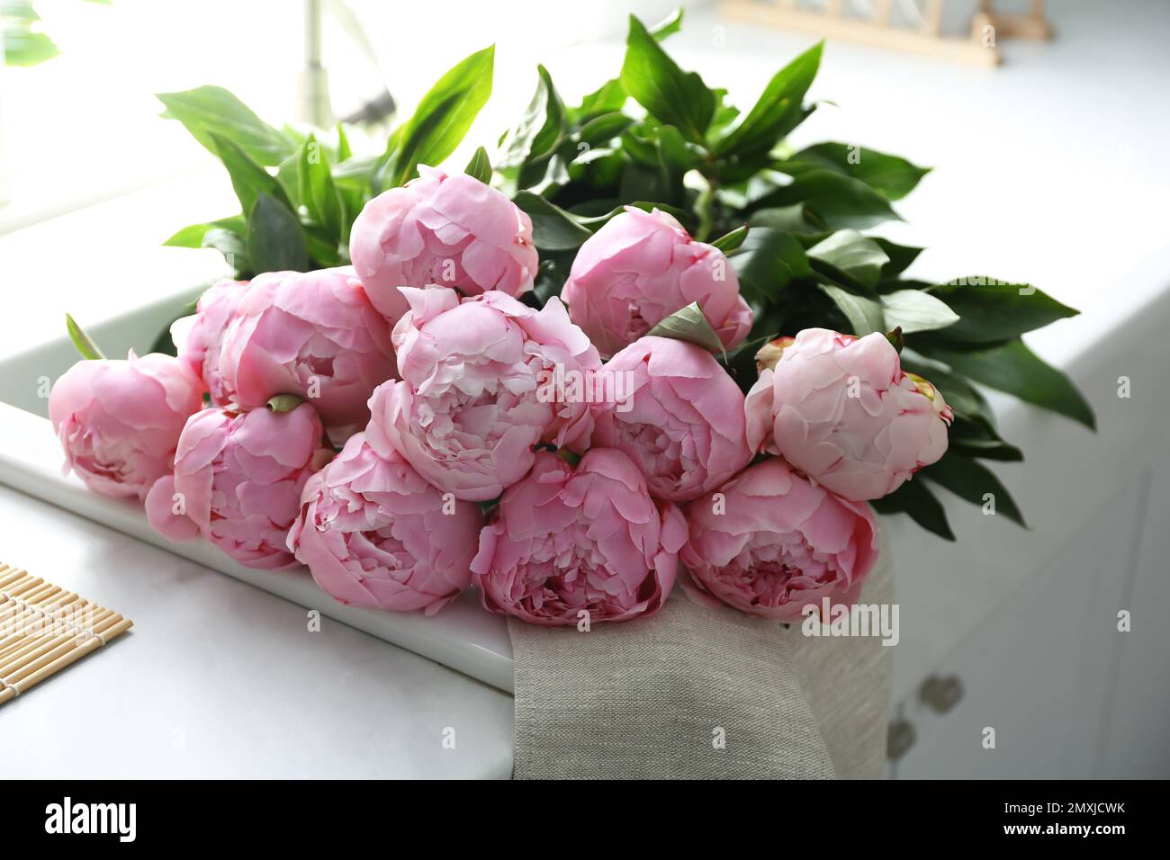 Bouquet of beautiful pink peonies on counter in kitchen Stock Photo