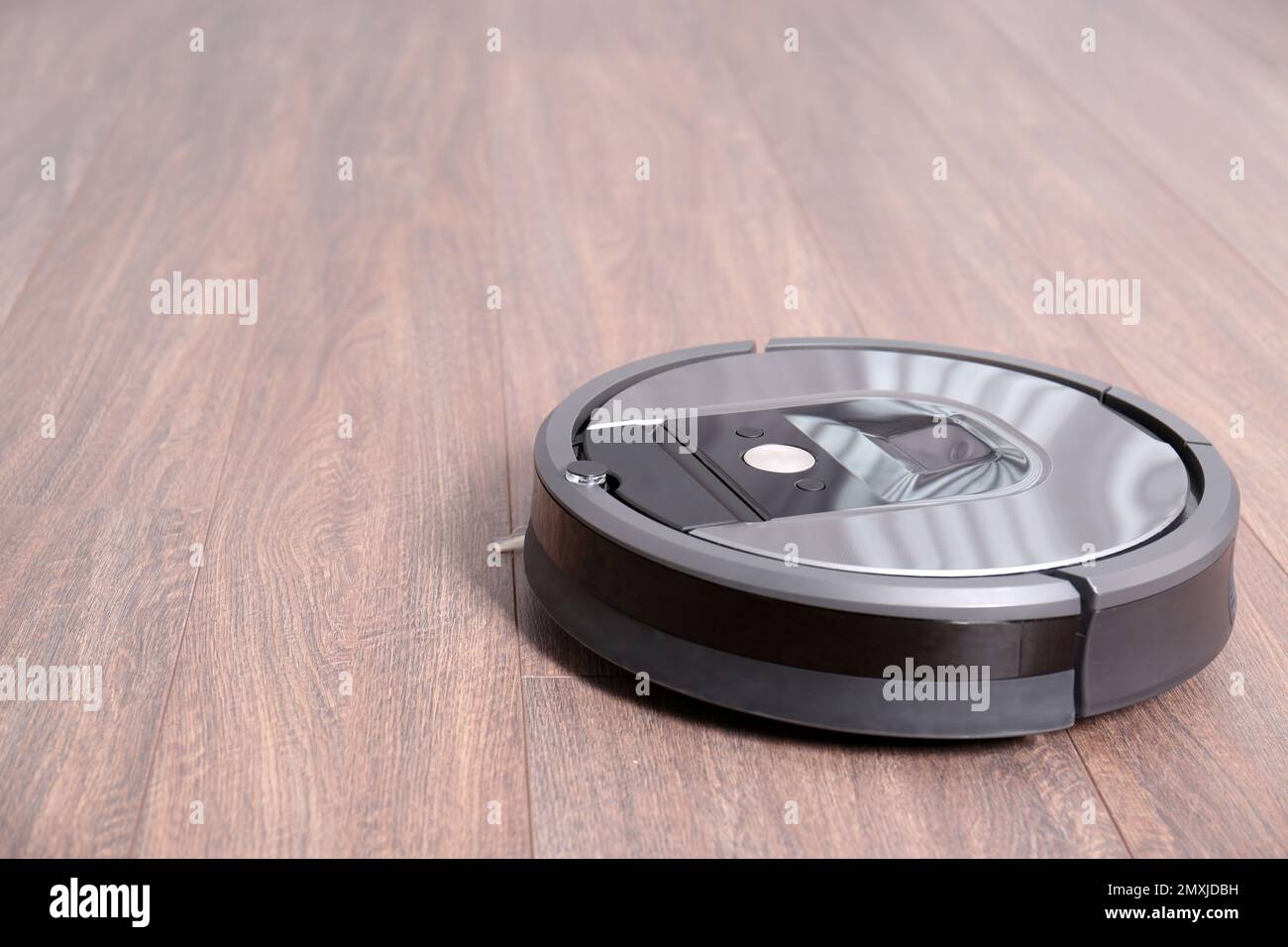 Hoovering floor with modern robotic vacuum cleaner indoors Stock Photo
