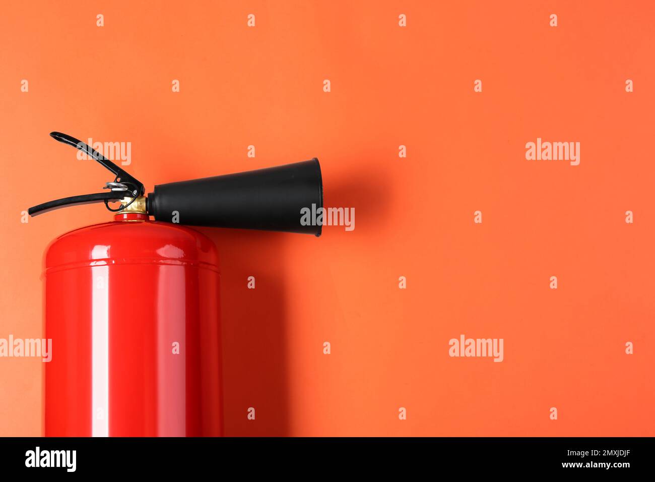 Fire extinguisher on orange background, top view. Space for text Stock