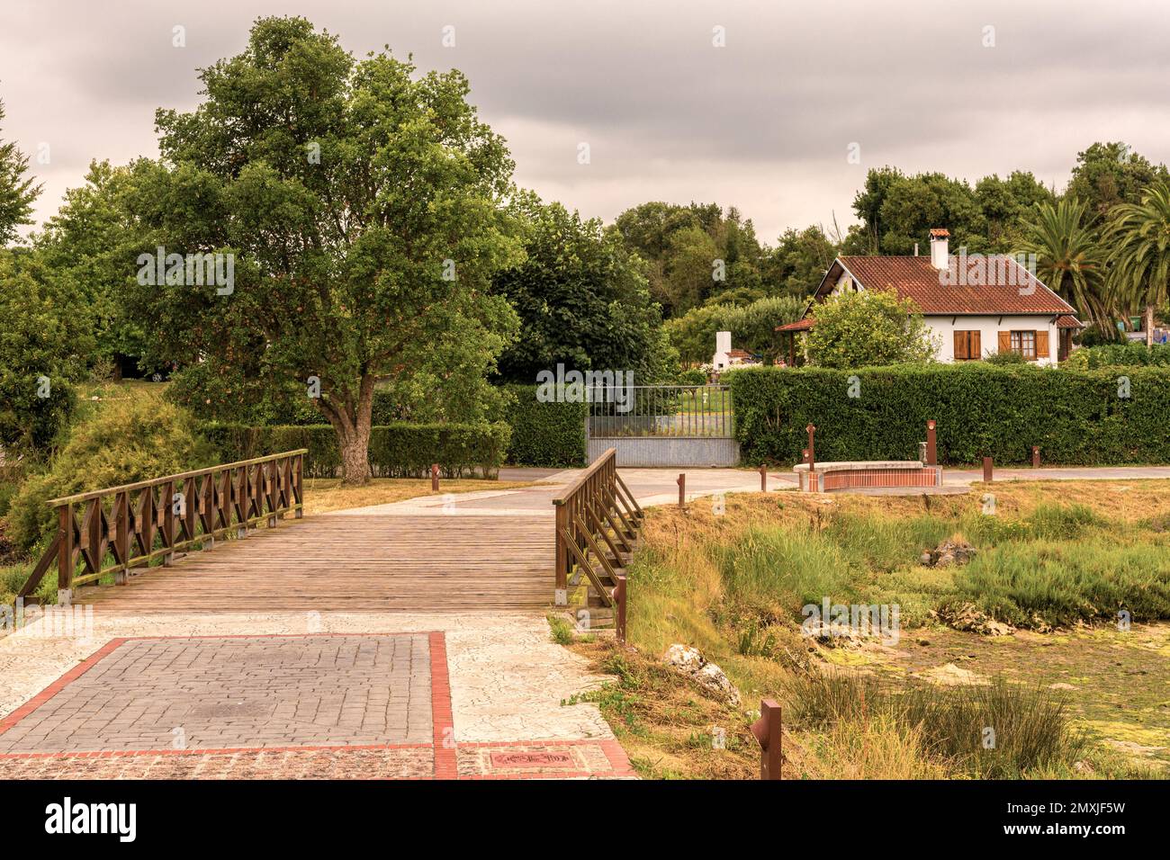 wooden bridge that leads to a chalet house with individual tree garden, private residence in the town of Argoños, Argonos, Cantabria, Spain, Europe. Stock Photo