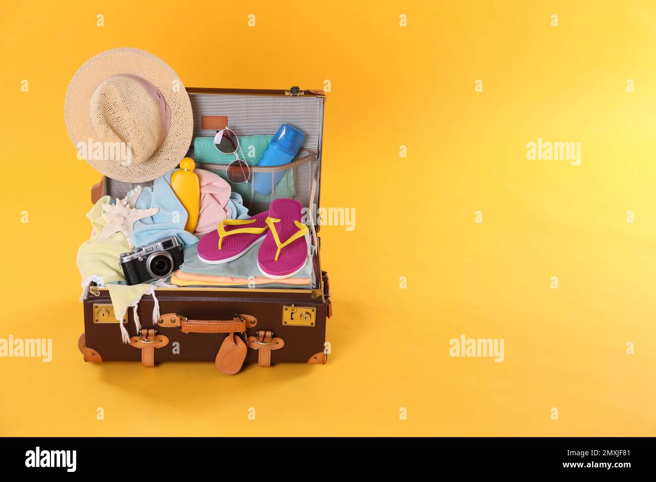 Packed vintage suitcase with different beach objects on orange ...