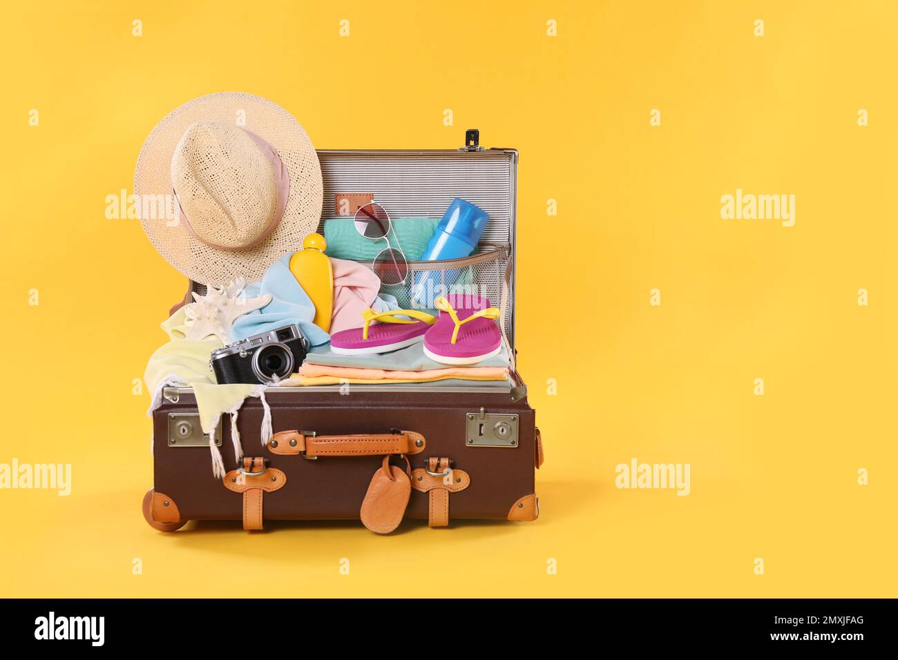 Packed vintage suitcase with different beach objects on orange ...