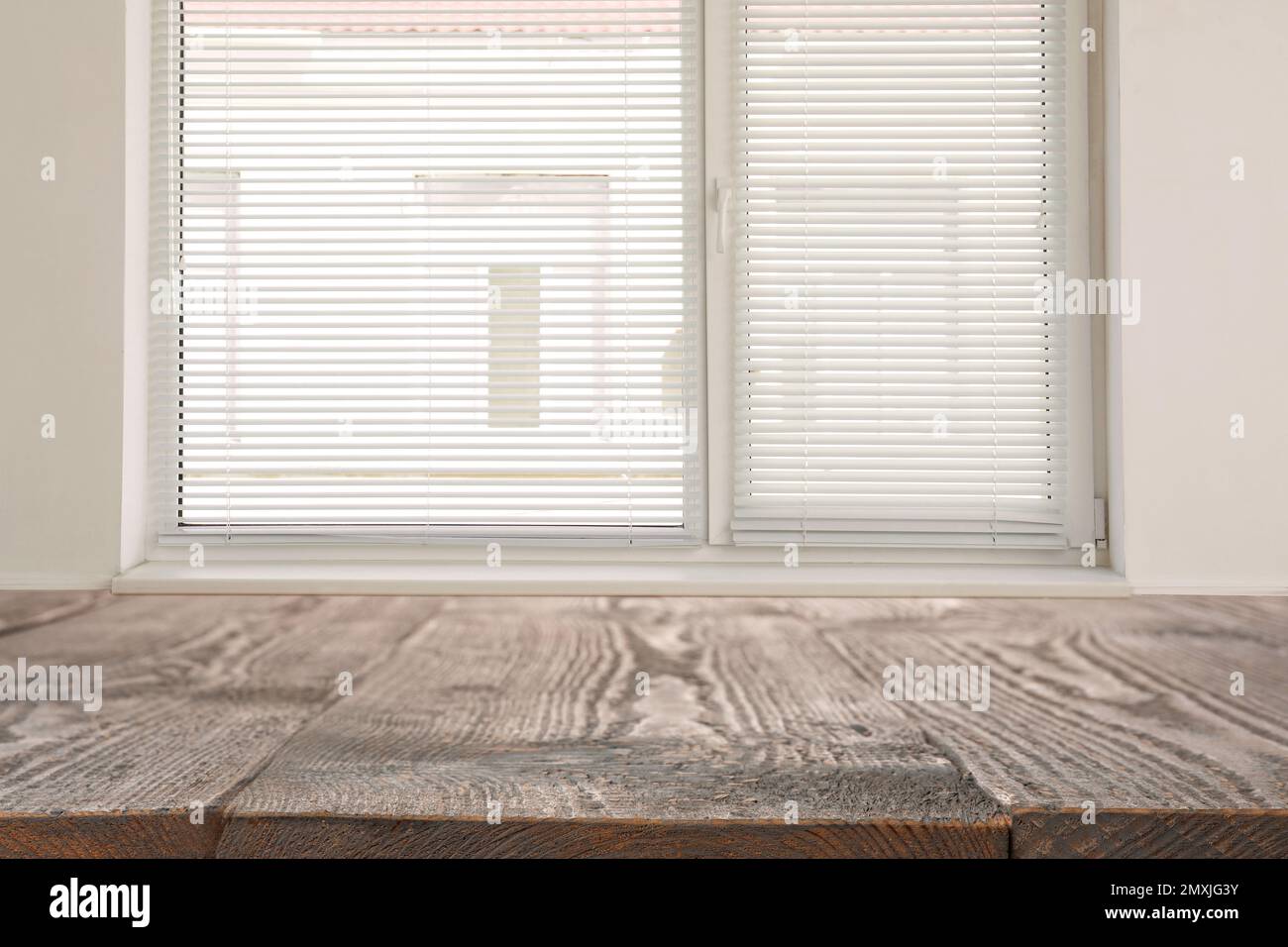 Wooden table and window with blinds on background Stock Photo - Alamy