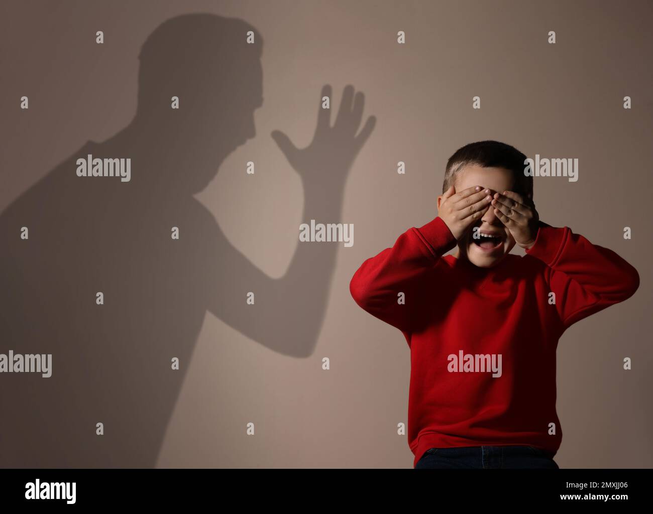 Child abuse. Father yelling at his son. Shadow of man on wall Stock Photo