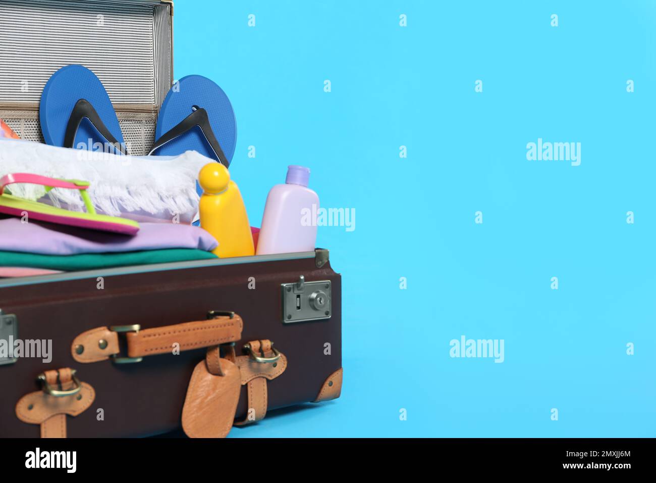 Packed vintage suitcase with different beach objects on light blue ...
