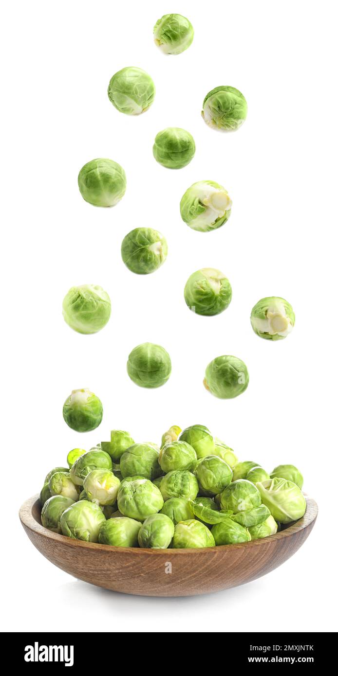 Fresh Brussels sprouts falling into bowl on white background Stock