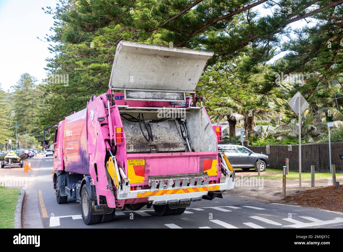 Pink garbage rubbish refuse truck in Palm Beach Sydney Australia picking up rubbish from street bins Stock Photo