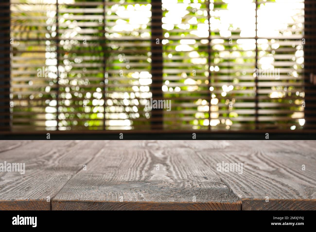 Wooden table and blurred window with blinds on background Stock Photo