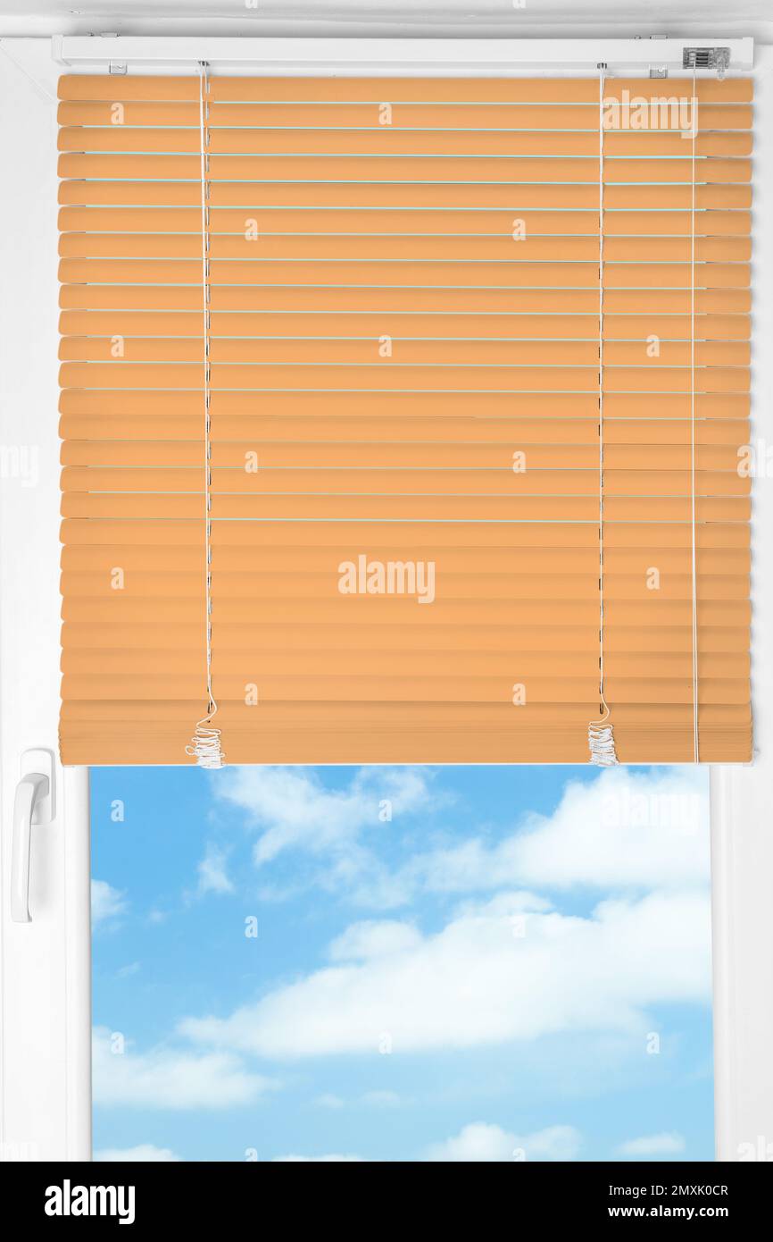 Window with modern orange blinds, closeup view Stock Photo
