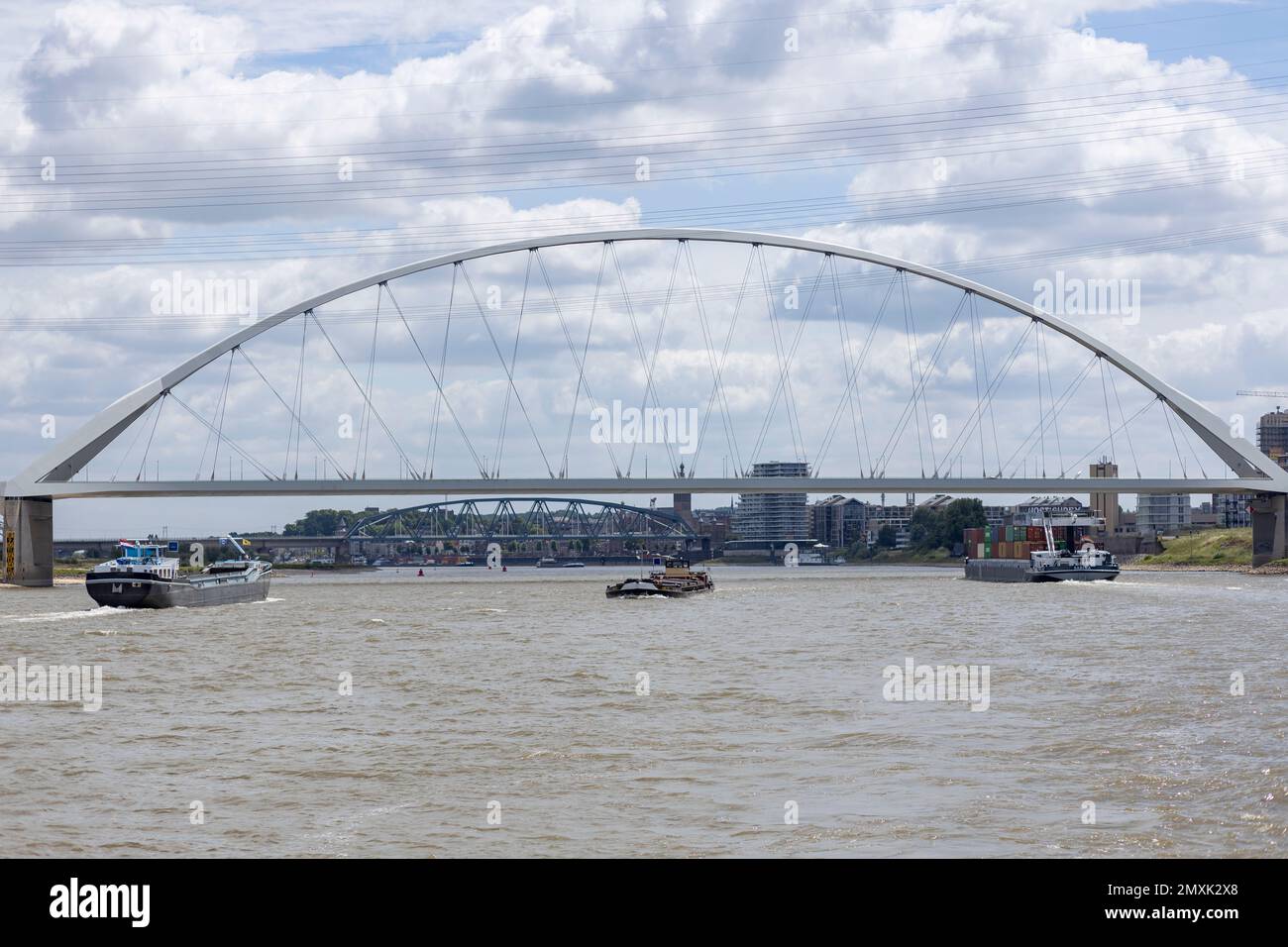 Cargo boats passing underneath Waalbrug bridge seen from the water. Stock Photo