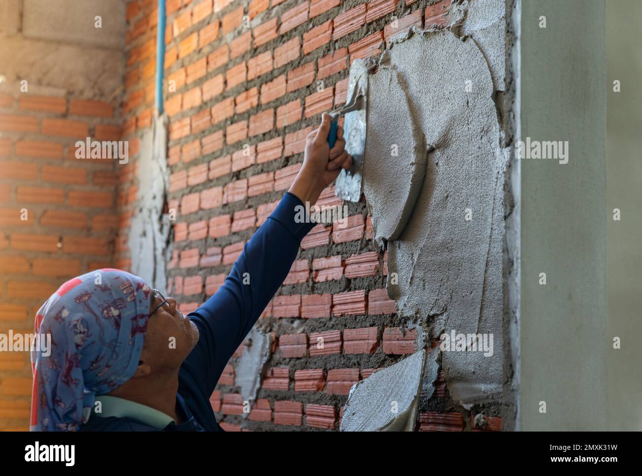Workers plastering brick walls in construction site. Stock Photo
