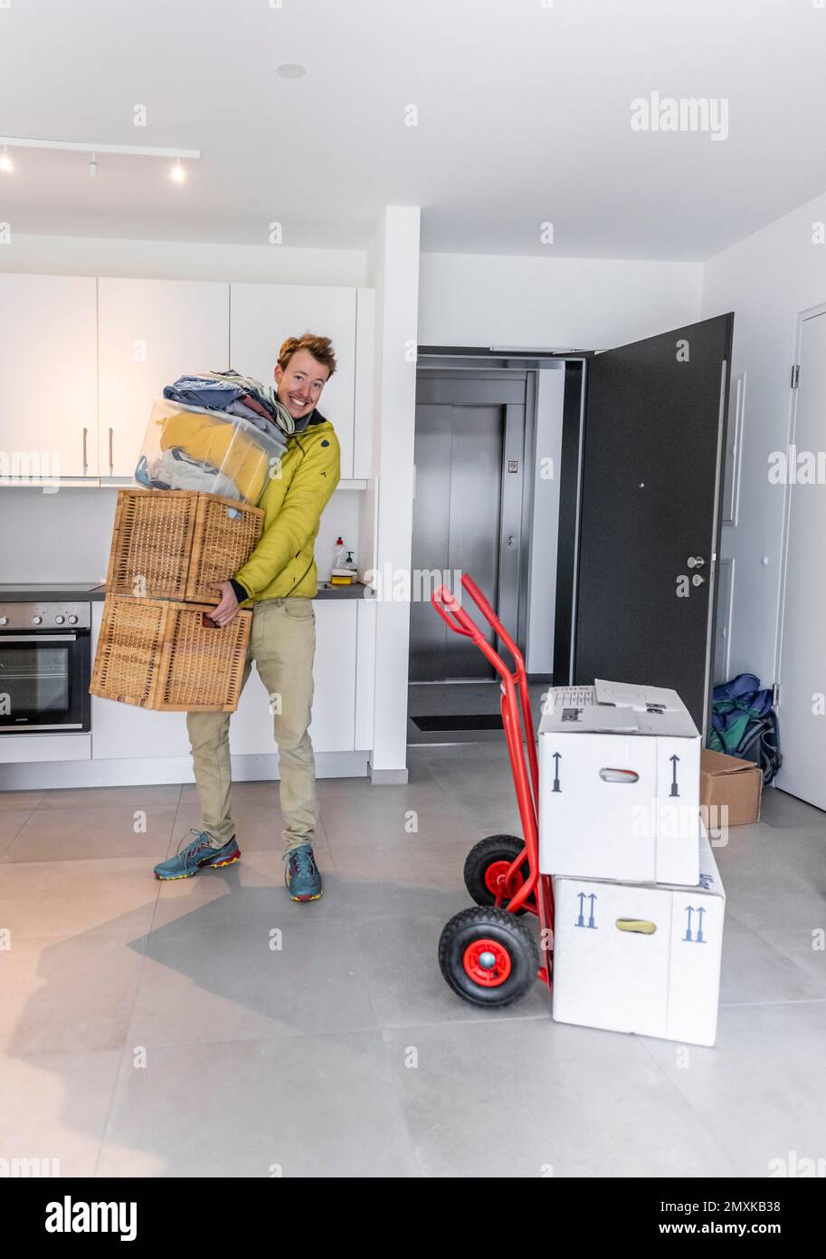 Young man with moving boxes, standing in modern kitchen of a flat