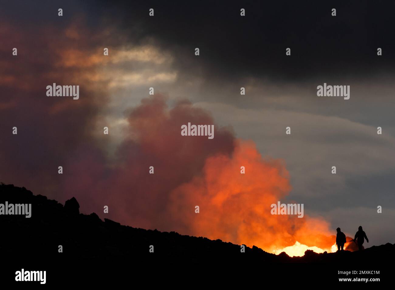 Tourists in front of reddish illuminated smoke cloud, erupting volcano, Fagradalsfjall table volcano, Krýsuvík volcano system, Reykjanes Peninsula, Ic Stock Photo