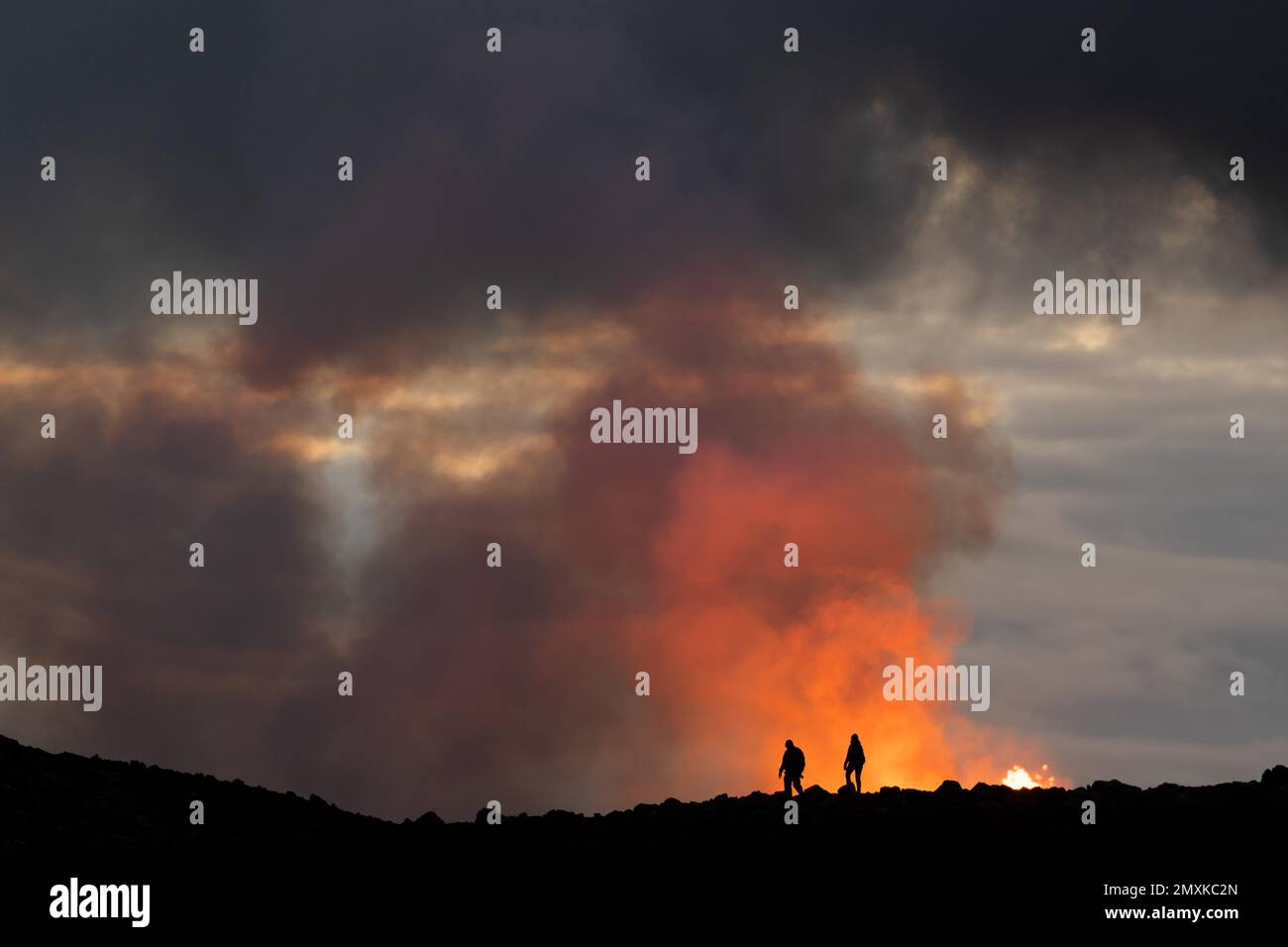 Tourists in front of reddish illuminated smoke cloud, erupting volcano, Fagradalsfjall table volcano, Krýsuvík volcano system, Reykjanes Peninsula, Ic Stock Photo