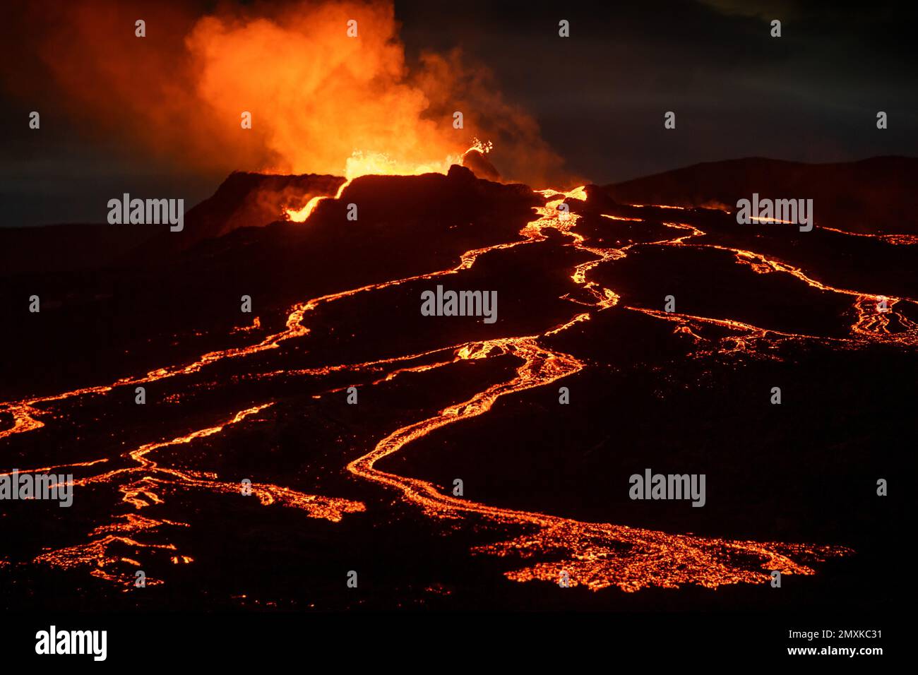 Lava spurting out of crater and reddish illuminated smoke cloud, lava flows, erupting volcano, Fagradalsfjall table volcano, Krýsuvík volcano system, Stock Photo