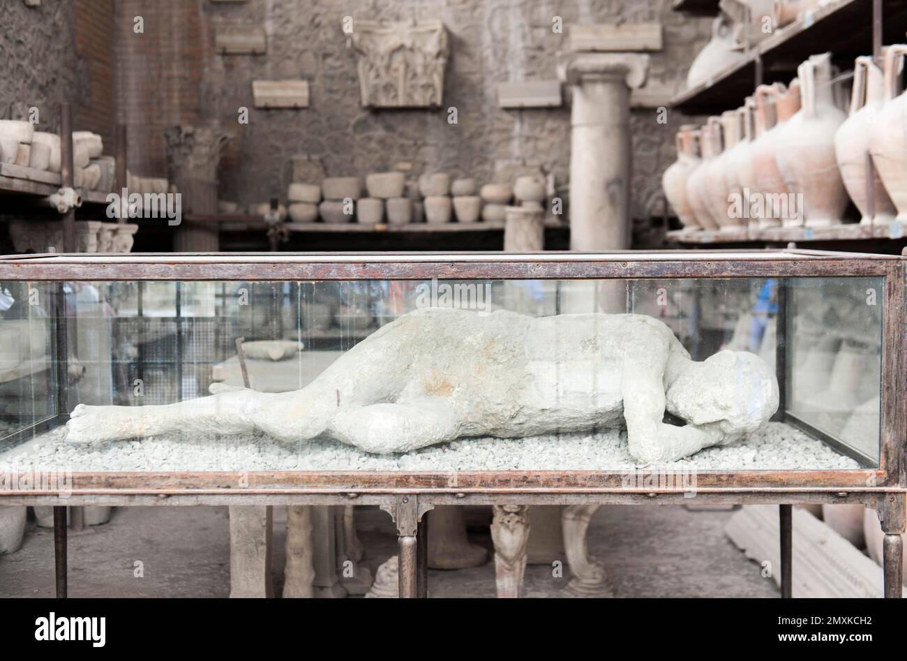 Archaeology, plaster cast of a reclining human in glass case in front of amphorae, ancient Roman city of Pompeii, Pompei, near Naples, Campania, Italy Stock Photo