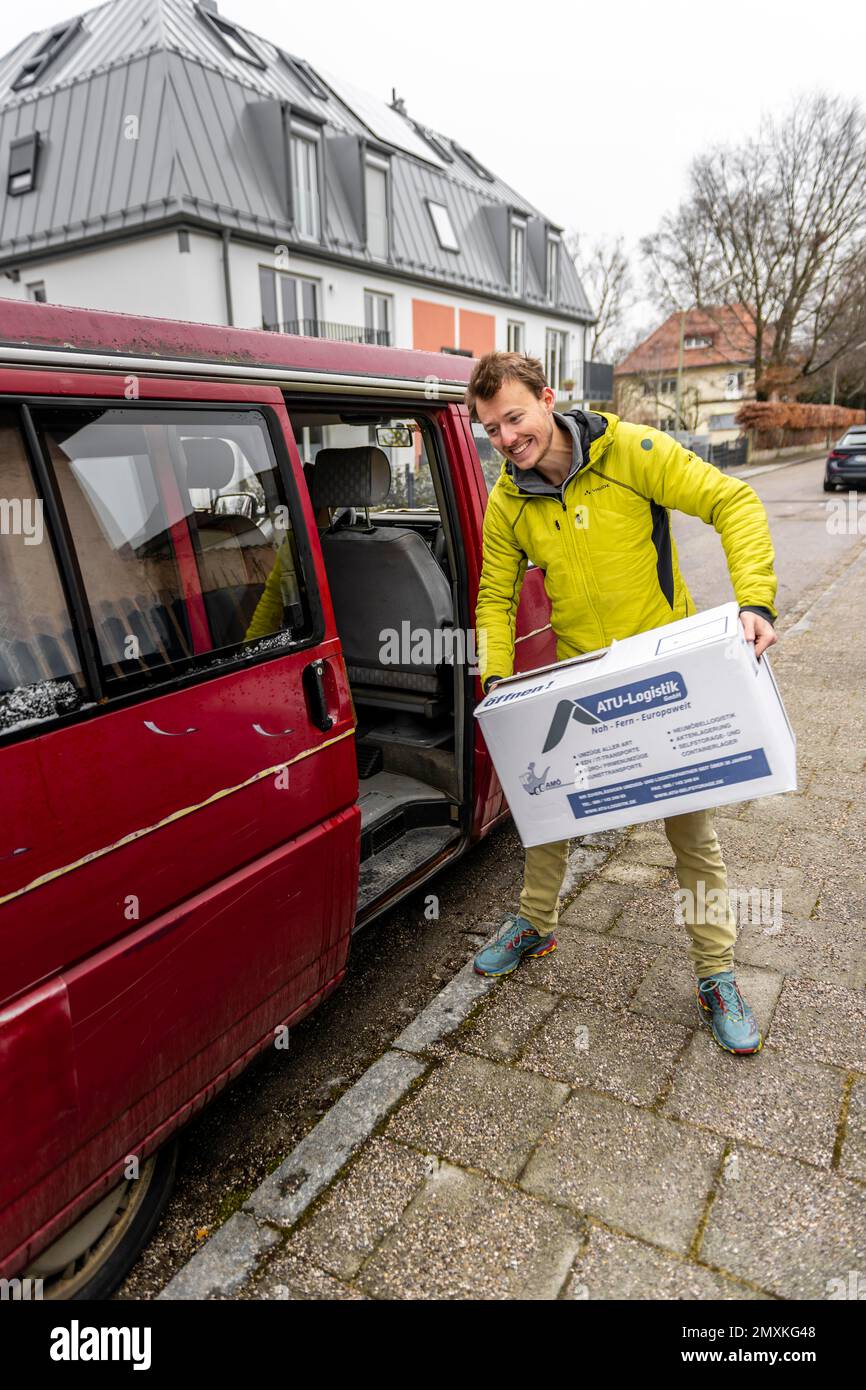 Young man clearing moving boxes from a car, moving to a new flat, Munich, Bavaria, Germany, Europe Stock Photo