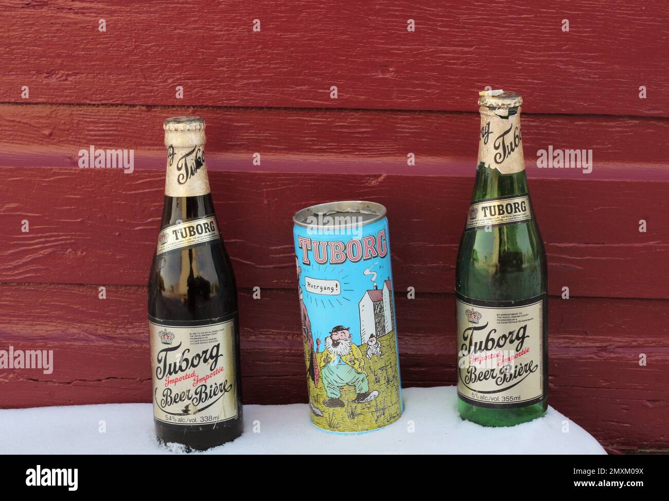 Two old beer bottles and one cartoon can in the snow against a wooden background. Stock Photo