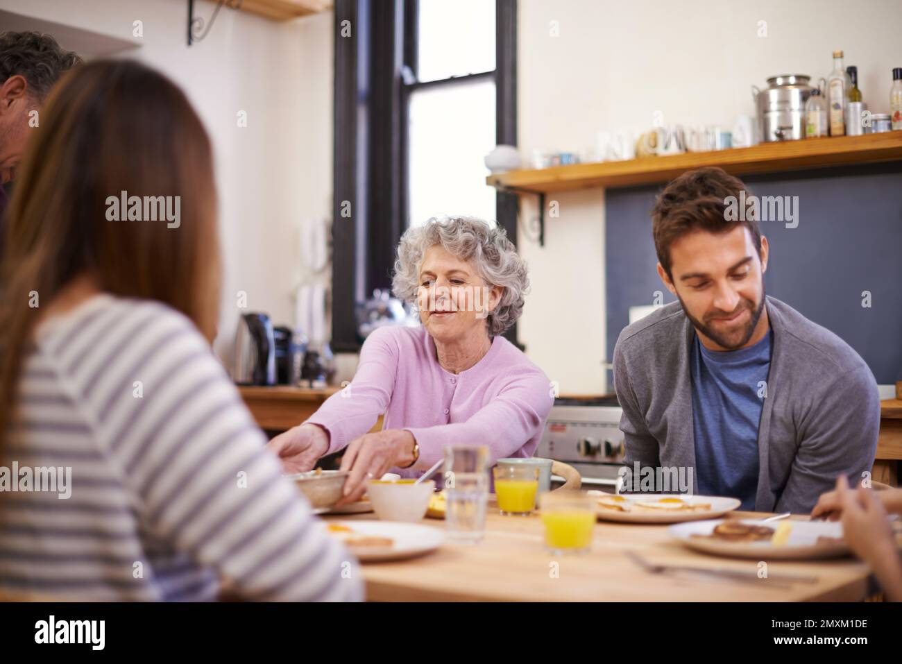 Nothing better than a hearty breakfast. a family eating breakfast around the kitchen table. Stock Photo