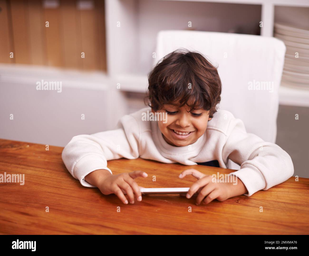Playing with tech toys. a little boy playing with a mobile phone at home. Stock Photo