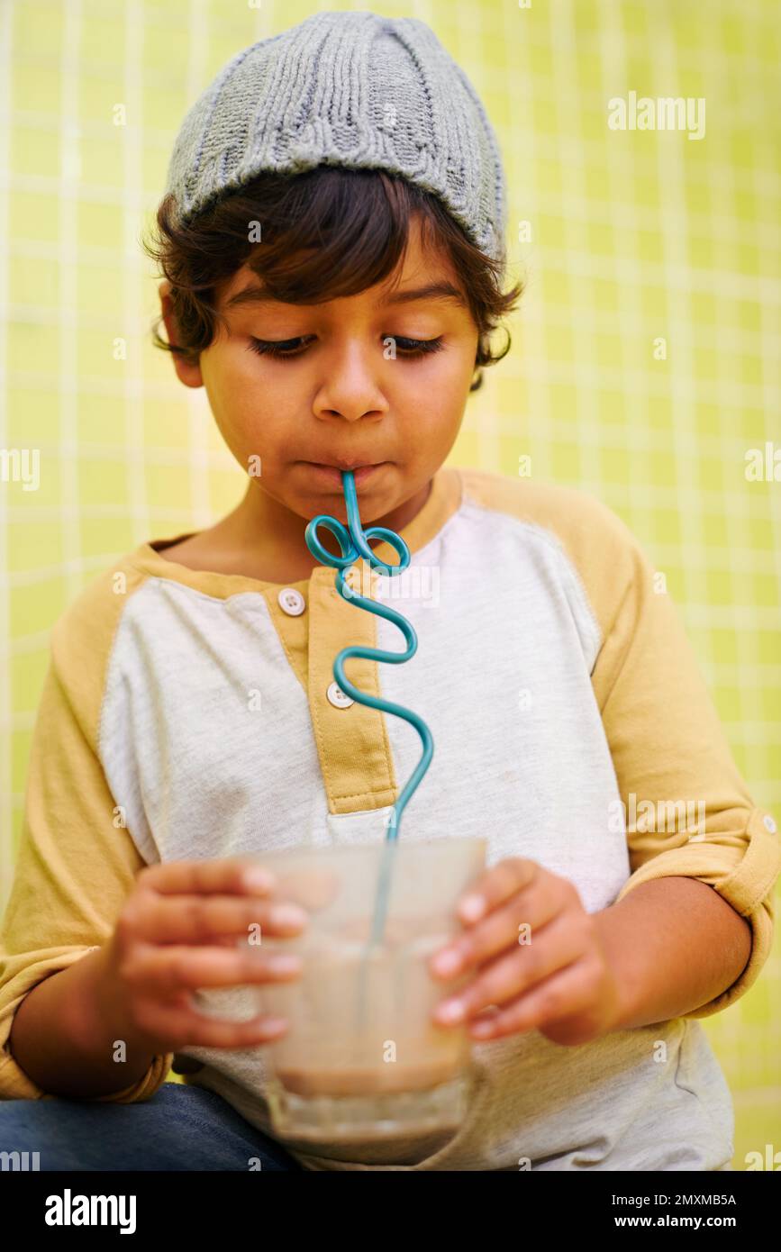 He loves his milkshakes. a cute little boy drinking a milkshake with a