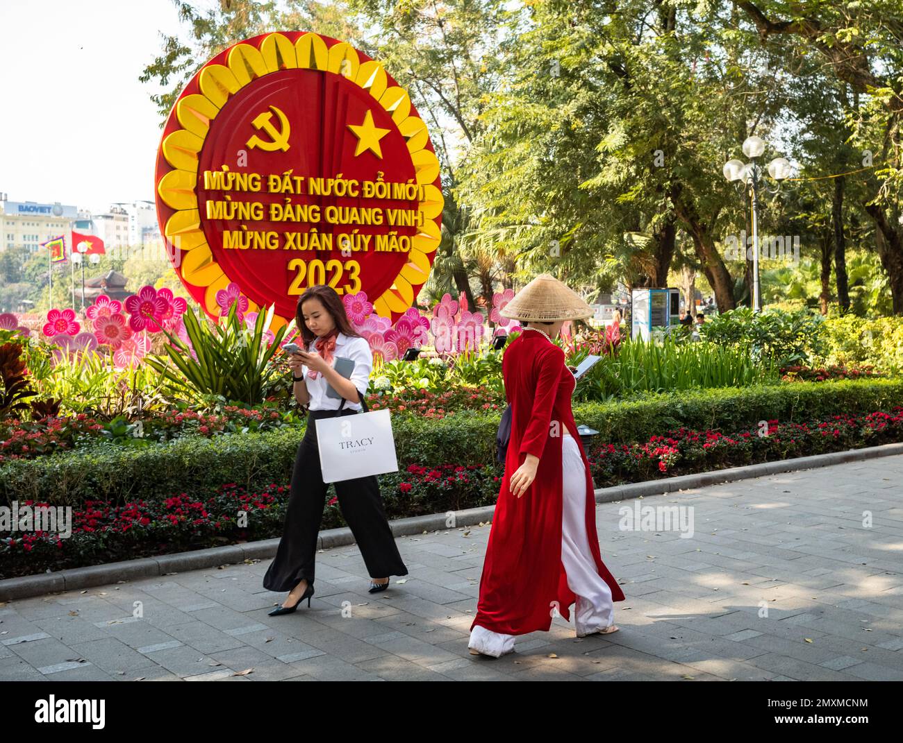 A woman dressed in traditional ao dai with a conical hat looks at her ...