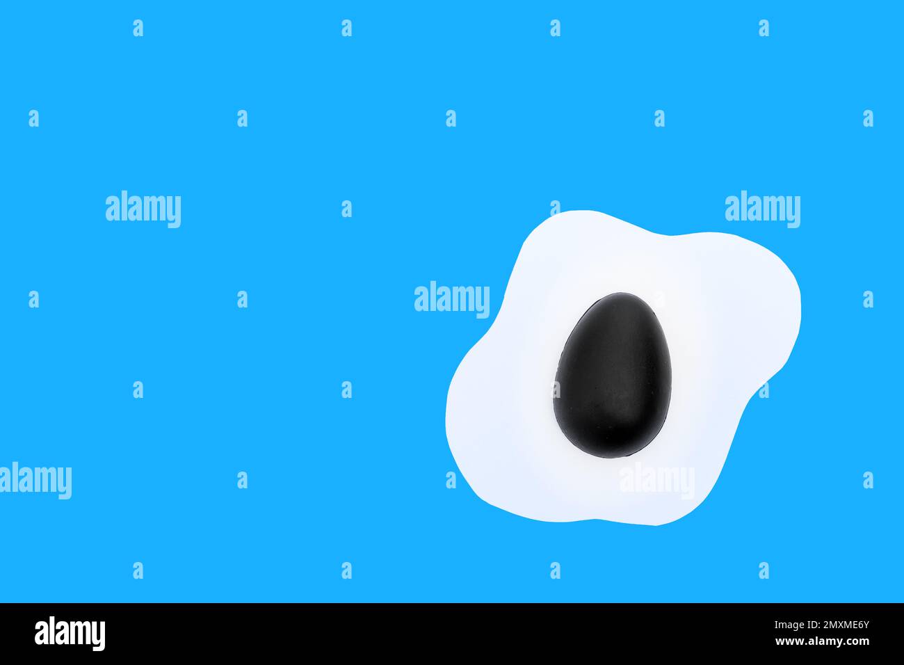 Creative layout made of scrambled eggs with painted black half Easter eggs on a blue background. Minimal Spring holidays concept. Stock Photo