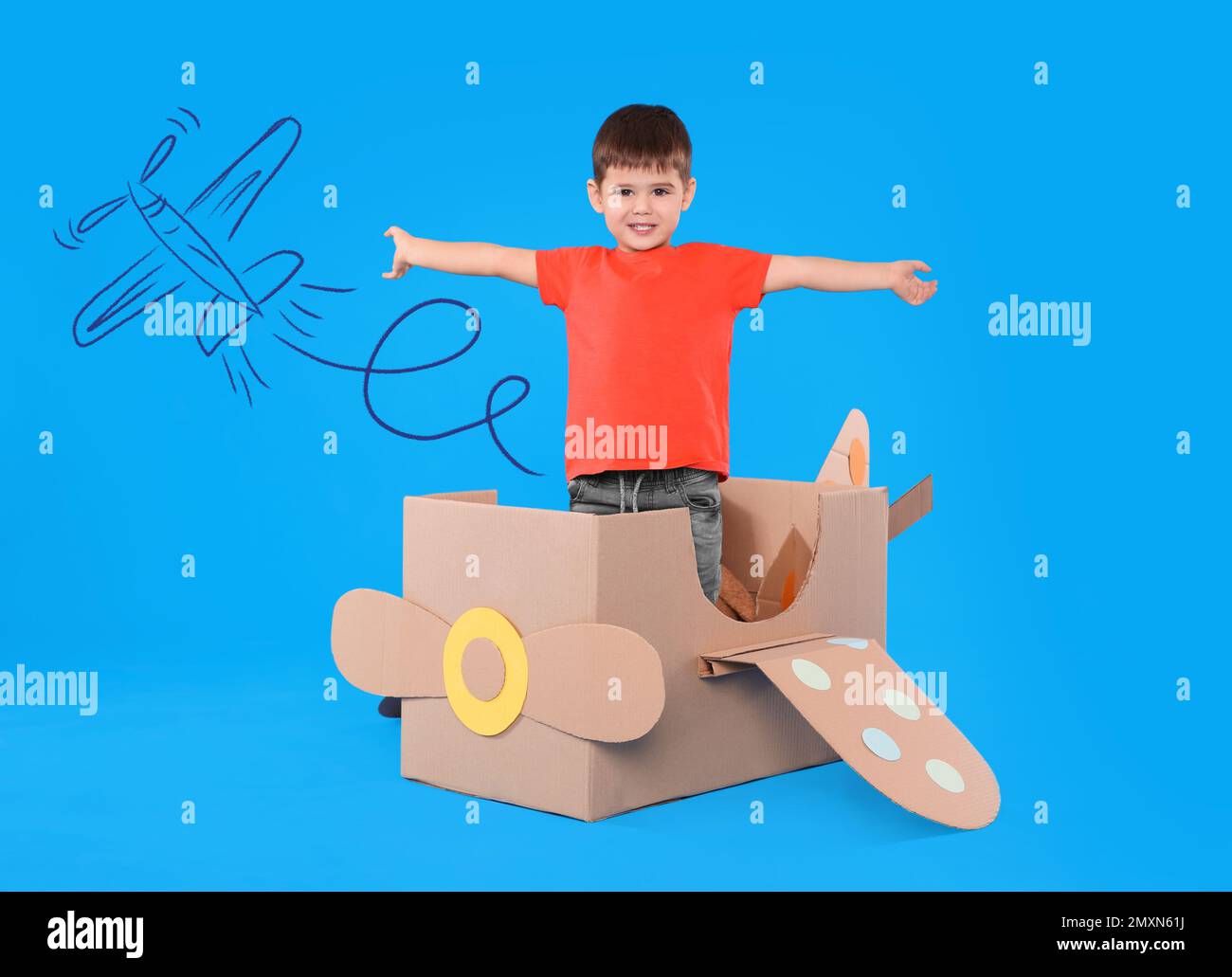 Cute little child playing in cardboard airplane on blue background with ...