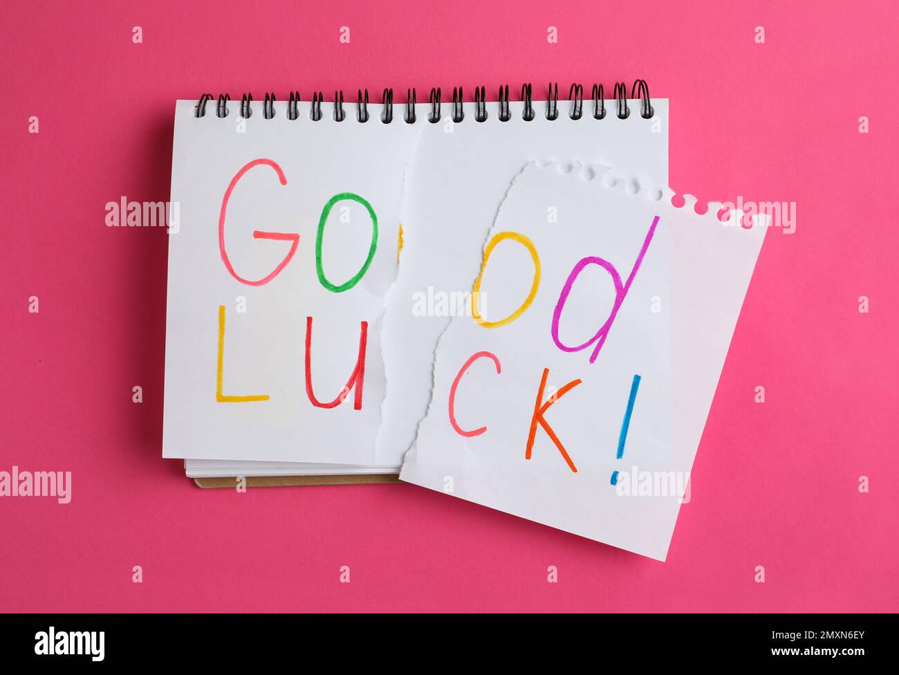 Torn phrase GOOD LUCK written in notebook on pink background, top view Stock Photo
