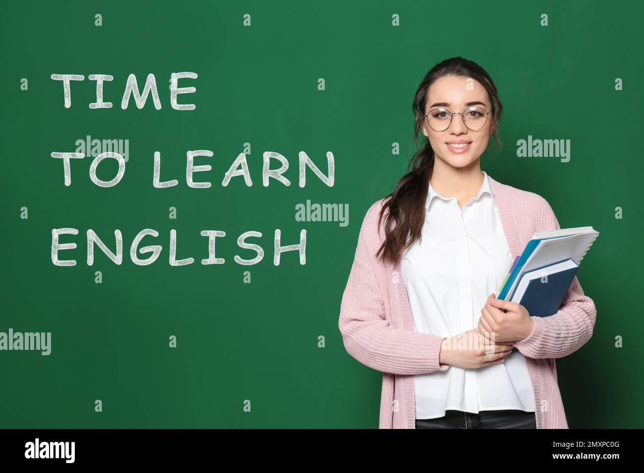 Beautiful teacher near green chalkboard with text time to learn english