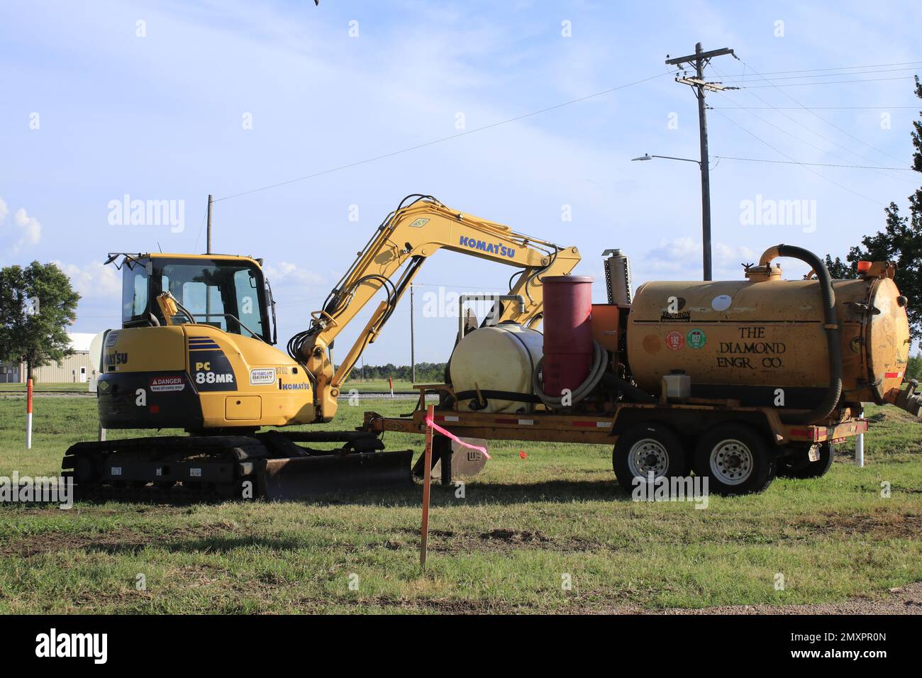 A KAMATSU EXCAVATOR with a tank blue sky and grass Stock Photo