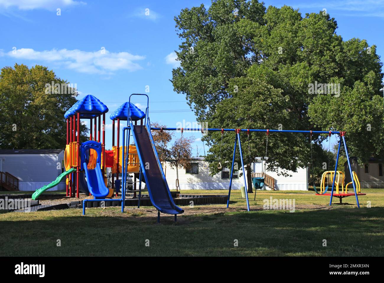 A Playground with blue sky and grass with tree's Stock Photo