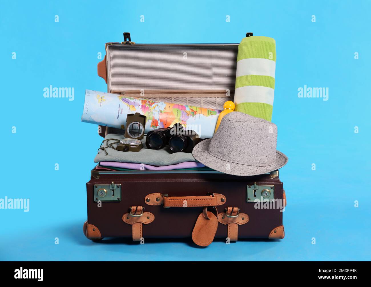Open vintage suitcase with clothes packed for summer vacation on light ...