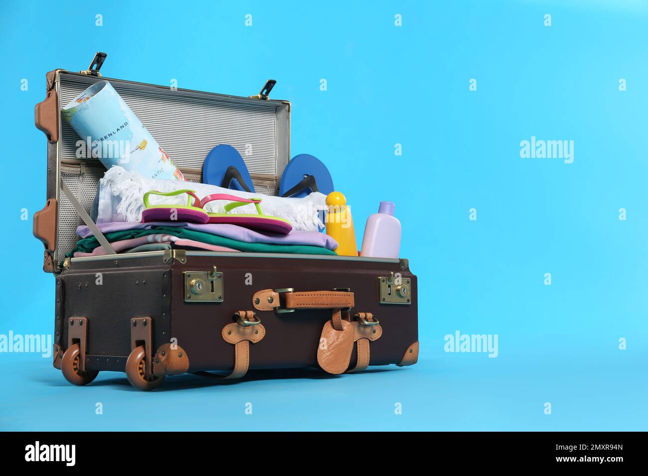 Packed vintage suitcase with different beach objects on light blue ...