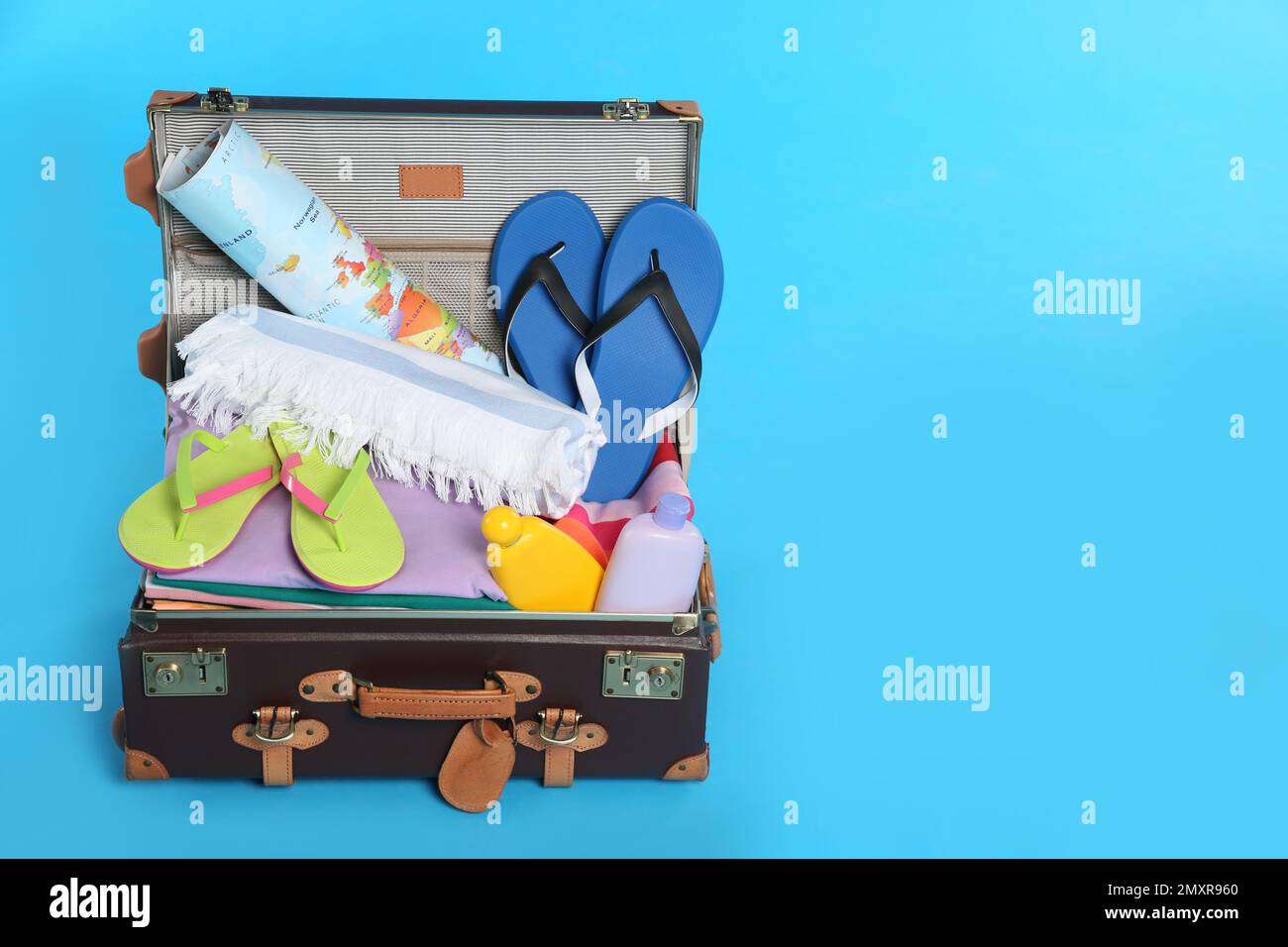 Packed vintage suitcase with different beach objects on light blue ...