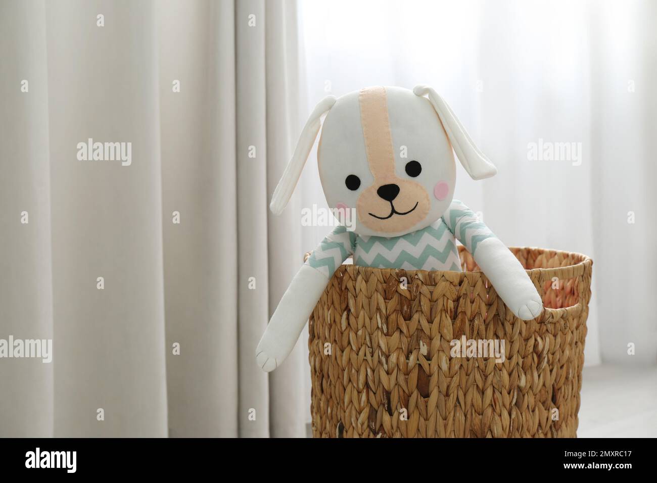 Funny toy dog in basket near window. Decor for children's room interior Stock Photo Alamy