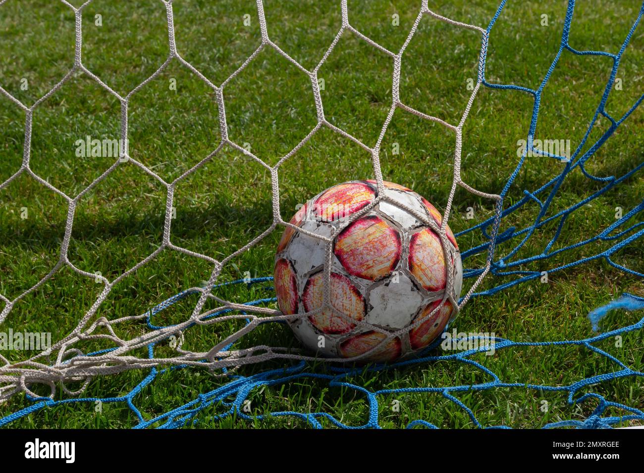 old soccer ball in the net on the background of grass soccer field