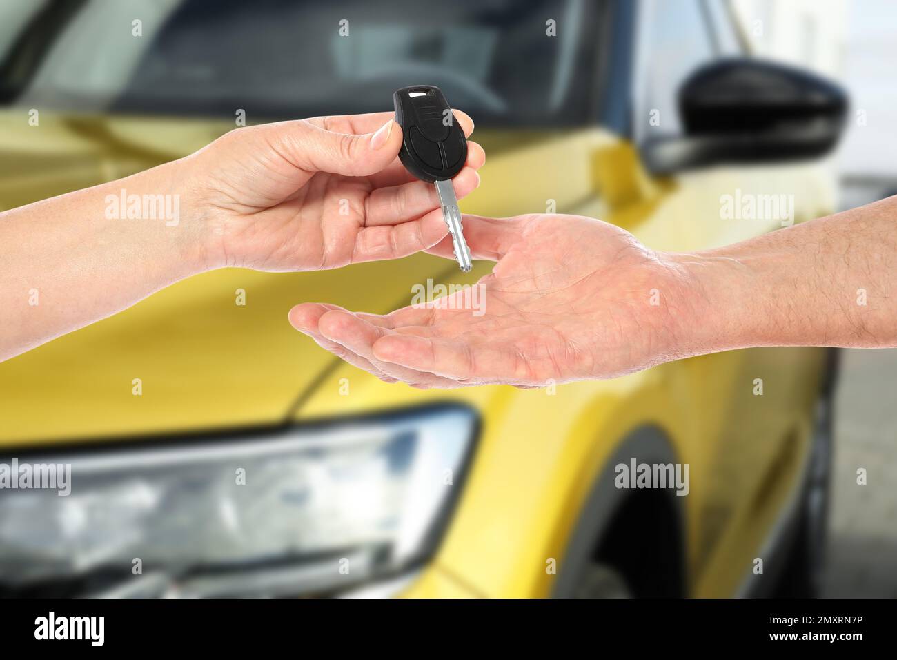 Car buying. Woman giving key to new owner against blurred automobile ...