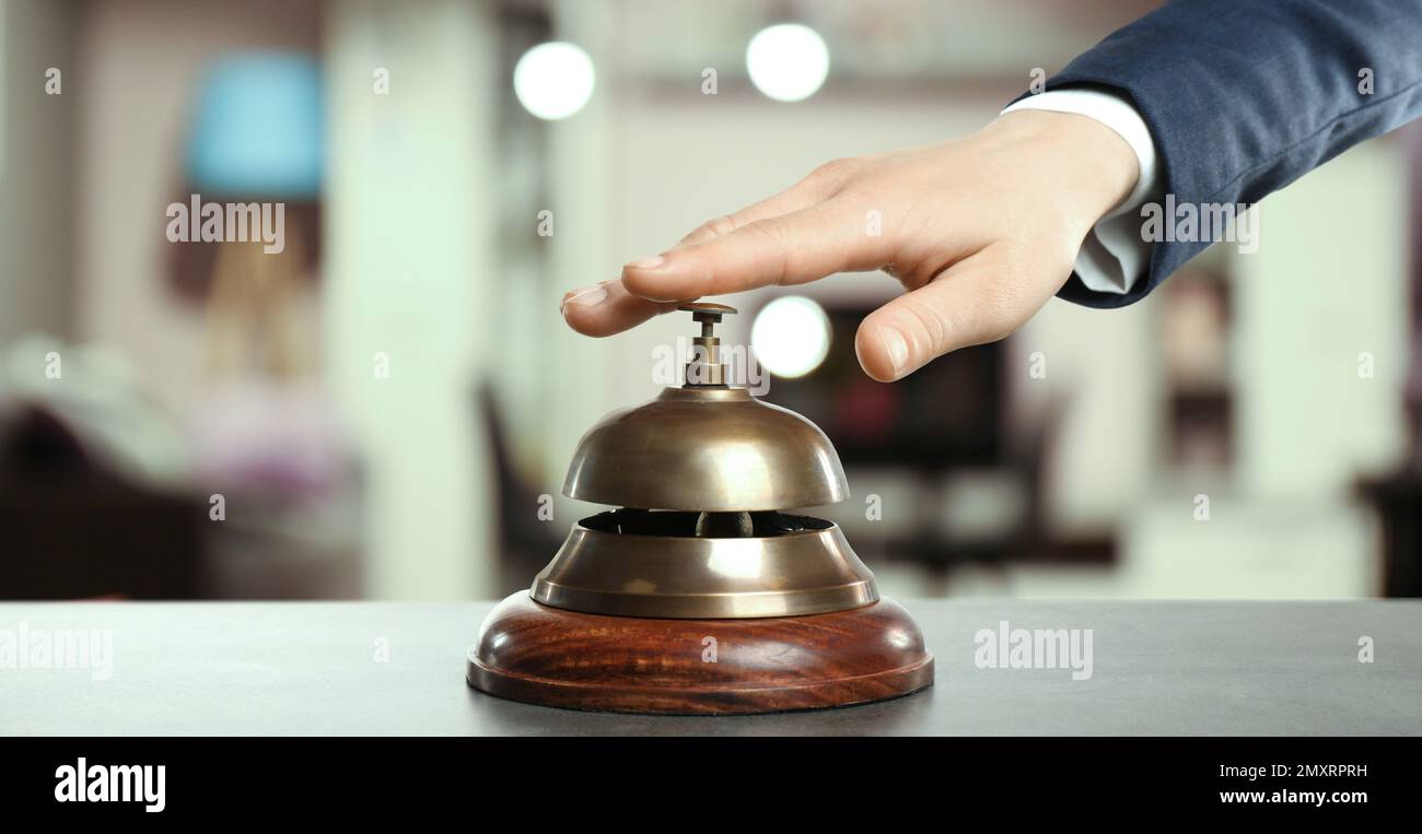 Man ringing hotel service bell on blurred background, closeup. Banner ...